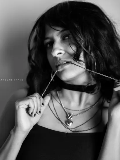 A monochrome shot from the 'Raw Rebellion' series. Playing with layered chains and a choker, this close-up captures a moody and defiant spirit ideal for edgy fashion campaigns.