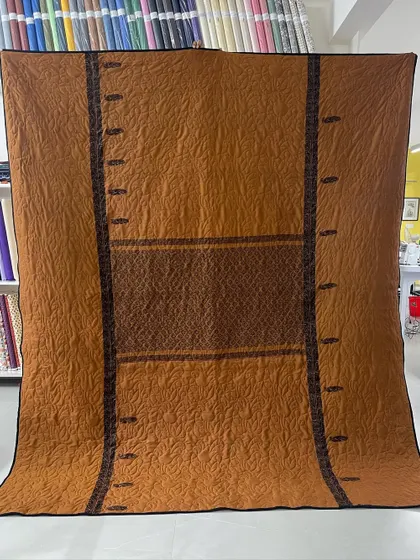The reverse side of the two-in-one saree quilt, featuring a warm orange tone and showcasing the original border design.