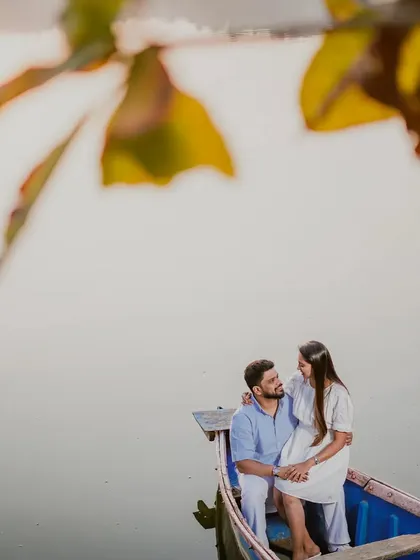 A serene portrait of the couple on a boat, framed by leaves to create a sense of intimacy.