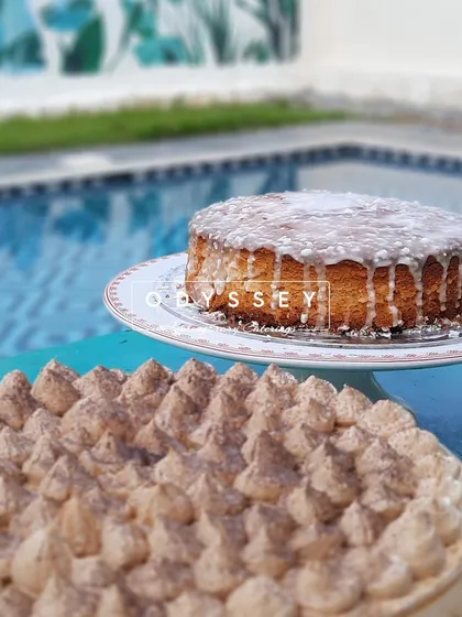 Sweetness by the poolside. This image features a classic glazed cake and a tiramisu, part of our array of desserts crafted to be the delicious conclusion to any fiesta.