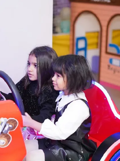 Two girls take the wheel together in one of our car racing arcade games.