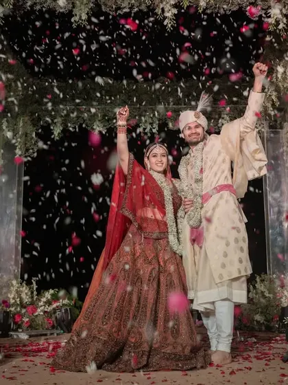 A joyous celebration as the couple stands under a shower of petals in their modern acrylic mandap, a perfect end to a beautiful ceremony.
