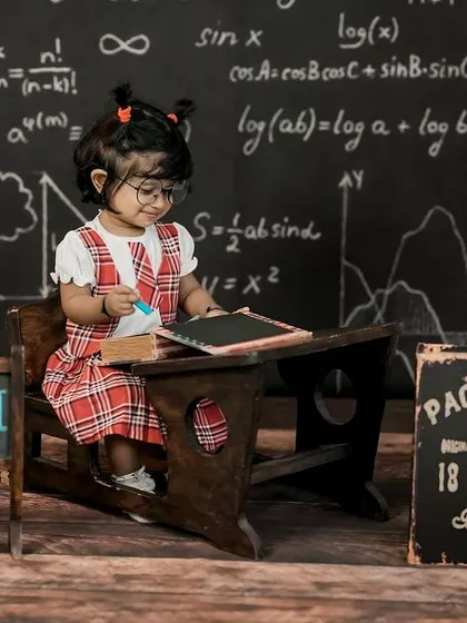 Back to school! This adorable little student is ready to learn at her vintage desk, with a chalkboard full of equations in the background.