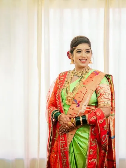 A happy Maharashtrian bride, glowing in her green and red saree, captured in a bright and airy portrait.