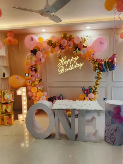 For this first birthday, I designed a magical butterfly theme. The setup includes a custom 'ONE' table for the cake, a shimmering balloon arch, and a personalized neon sign, all coming together to create a whimsical party space.