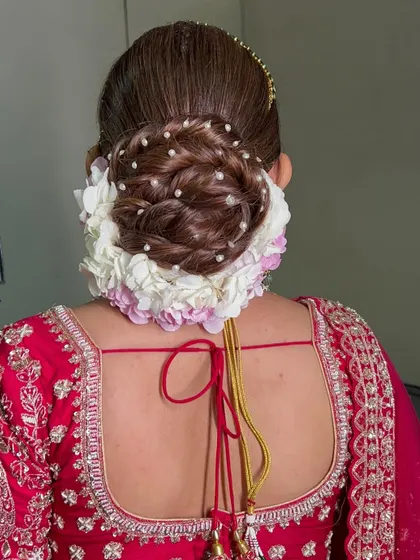 This twisted bridal bun is decorated with beautiful hydrangea flowers and small pearl details. The twists add texture and dimension, making it a unique and elegant choice.