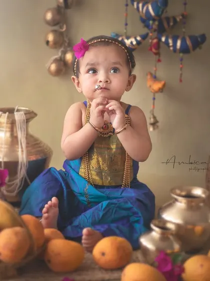 A thoughtful moment captured during the mango-themed sitter session. The baby's contemplative expression adds a layer of sweet innocence to the vibrant, cultural setup.