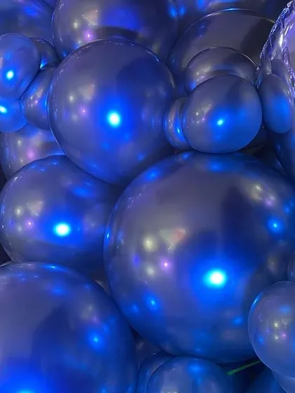 Another artistic close-up of the chrome balloons, highlighting their unique shine and the blue lighting.