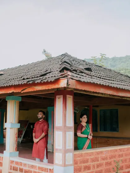 An architectural shot of a couple on the veranda of a rustic house during their pre-wedding session.