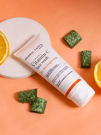 A clean, minimalist flatlay of a Vitamin C face wash with orange slices and aloe vera pieces. The composition is modern and fresh, perfect for a brand that emphasizes natural ingredients.