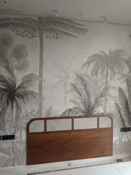 A monochromatic jungle mural installed behind a headboard, creating a stunning and artistic feature wall in a bedroom.