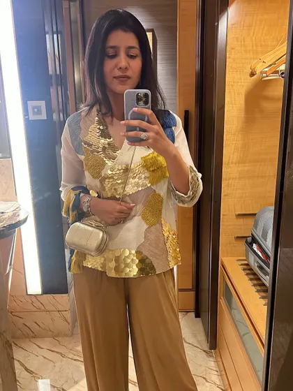 This look is all about modern festive wear. A statement top with gold sequin detailing paired with simple beige trousers creates a chic and sophisticated outfit for any celebration.