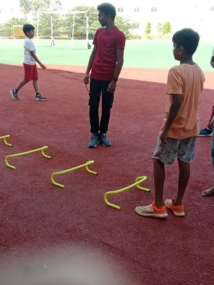 Students participate in agility drills with hurdles during an outdoor sports session, improving their speed and coordination.