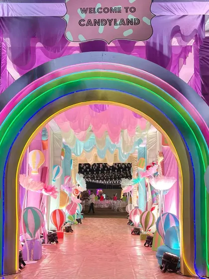 A dreamy rainbow entrance welcoming guests to a whimsical Candyland, complete with hot air balloon props and pastel drapes.