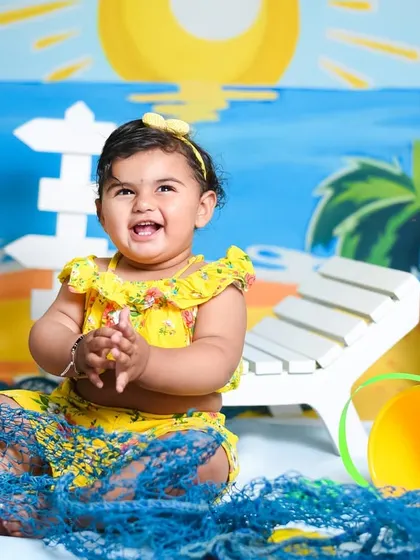 Pure happiness captured during Aarna's beach-themed session. The colorful props and her bright yellow outfit make for such a cheerful photo.