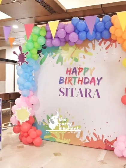 This 'Art Attack' birthday party featured a vibrant photo backdrop with a colorful paint splatter design, framed by a rainbow balloon arch. It was the perfect spot for creative and fun photos.