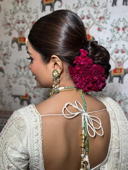 A detailed shot of the elegant bun with deep red flowers, adding a beautiful pop of color to the all-white look.