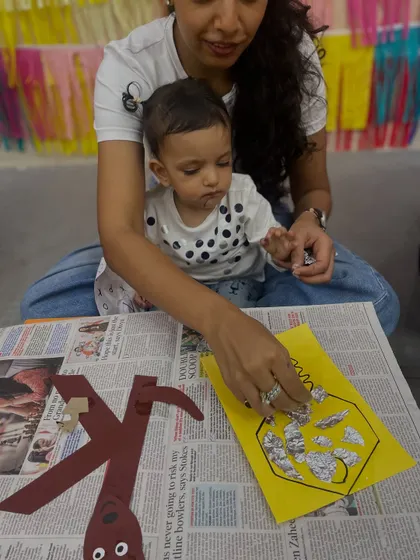 A toddler is engrossed in a sensory craft activity, pasting foil onto a key shape. This tactile experience is great for sensory development.