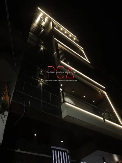 A dramatic, low-angle night shot of The Cursive Abode's facade. The linear lighting traces the architectural edges, creating a visually stunning effect.