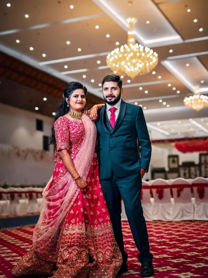 A classic wedding reception look. The couple stands against a beautiful floral wall, ready to greet their guests in a hall that I've decorated to feel grand and welcoming.