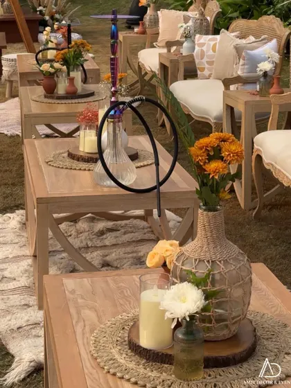 A close-up of the boho table decor, featuring a hookah, candles on a wooden slice, and floral arrangements in woven vases.