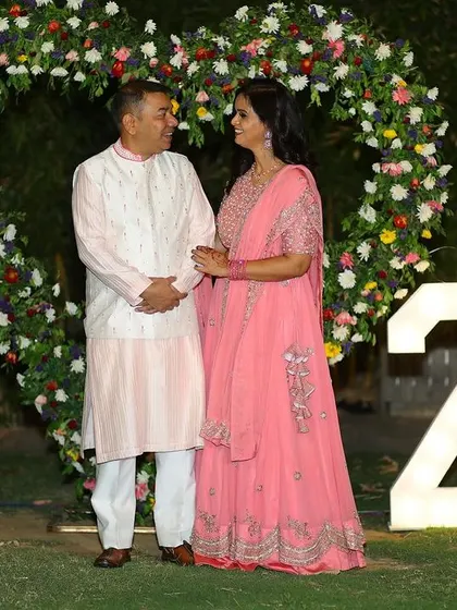 The couple posing for a photo in front of the heart-shaped floral arch and "25" lights. It’s the perfect photo spot to capture memories.