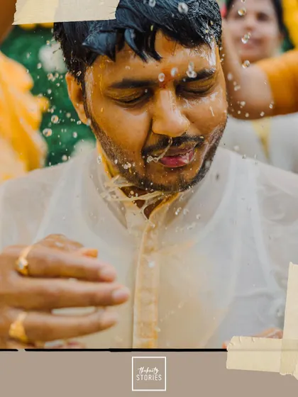 A close-up of the groom being doused with water, capturing his reaction in a fun, candid moment.