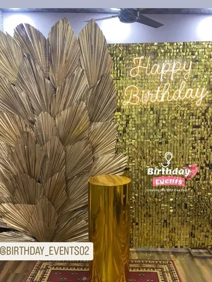 A luxurious combination of a gold sequin wall and a fan of dried gold palm leaves. This setup is perfect for a sophisticated, high-fashion birthday theme.