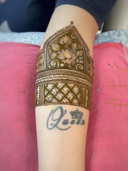 The finished arm band design incorporating the client's tattoo. The mehndi complements the existing ink perfectly.