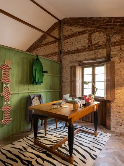 My personal cabin within the restored studio. We left the original brick and stone walls exposed, pairing them with a bold zebra-print rug and a simple wooden desk. It’s a space where the building's raw history meets my own creative energy.