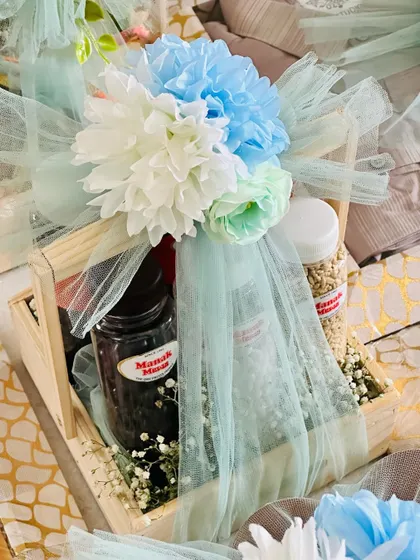 A close-up of a snack hamper, showing the artful arrangement of jars and the delicate tulle and floral wrapping.