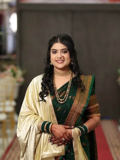 A full-length portrait of a gorgeous Maharashtrian bride. The green saree with a cream shawl is a classic combination, paired with glowing, natural makeup.