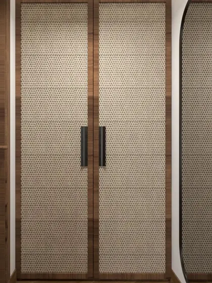 A detail shot of a wardrobe with cane or rattan-panelled doors. This natural material adds texture and warmth, perfect for creating a relaxed, tropical, or bohemian-inspired interior.