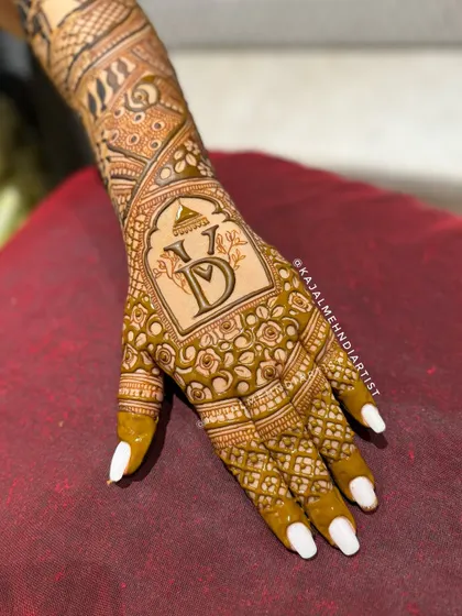 A close-up of a bridal backhand design, showcasing a custom wedding logo with the couple's initials, surrounded by a delicate floral pattern.