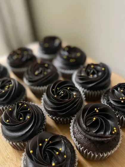 A batch of our elegant chocolate cupcakes, topped with rich chocolate frosting and delicate gold sprinkles. These were packed as return favors for a little one's birthday.