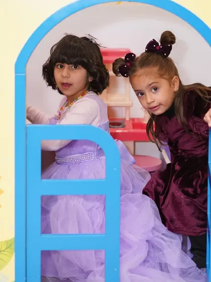 Two girls in princess dresses play inside one of our pretend-play houses.