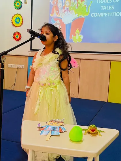 A student captivates the audience with her storytelling skills during the 'Trails of Tales' competition, using puppets to bring her story to life.