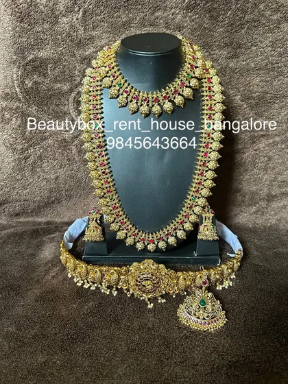 A classic mango mala set with red and green kemp stones. This rental includes a choker, long necklace, and a goddess motif vaddanam.