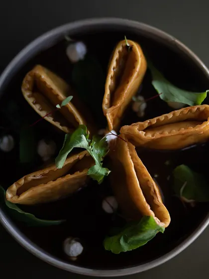 The beautiful star-like presentation of our Slow Cooked Lamb and Truffled Potato Doppio Agnolotti, floating in a dark, savory lamb jus.