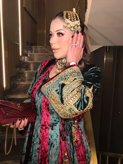 A side profile of the royal beauty, showcasing the intricate passajewelry and the glamorous eye makeup.