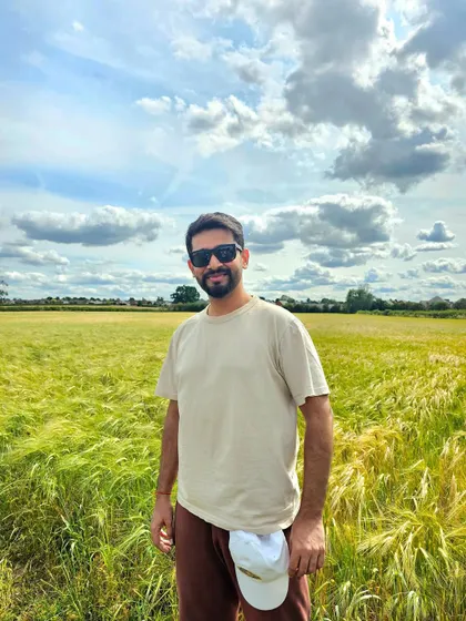A relaxed pose in a field in Leicester, UK. This image showcases a connection with nature and is suitable for brands promoting outdoor wear or a tranquil lifestyle.