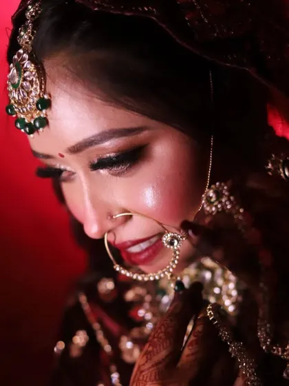 A profile shot focusing on the bride's delicate features, her intricate nath, and the glowing highlighter on her cheekbones.
