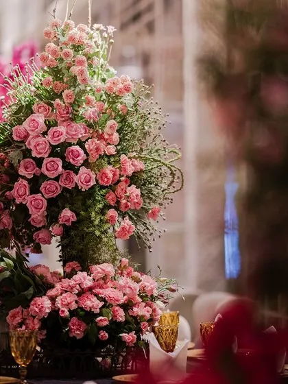 A large arrangement of pink roses and baby's breath, providing a soft, romantic counterpoint to the dramatic black and fuchsia elements of the decor.