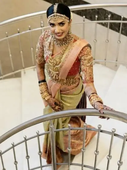 A full-length view of a stunning South Indian bride, showcasing the complete look from the elaborate hair jewellery down to the perfectly draped saree.