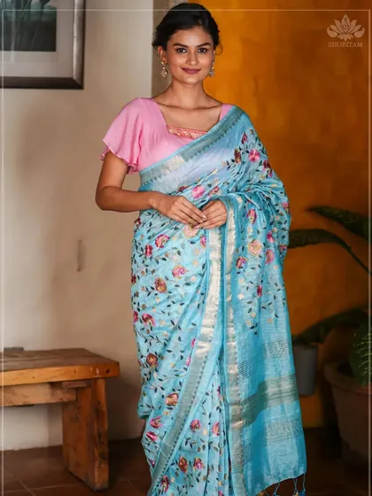 A beautiful sky-blue linen saree with delicate floral embroidery. This piece is light, airy, and perfect for a summer brunch or a day event.