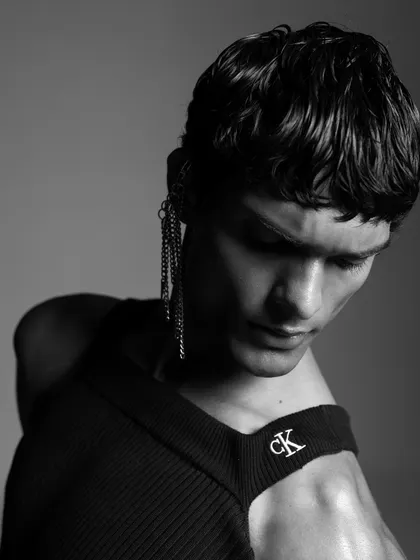 A detailed shot focusing on an unconventional way of styling a Calvin Klein top. The addition of a chain earring adds an edgy, editorial element to the overall look.
