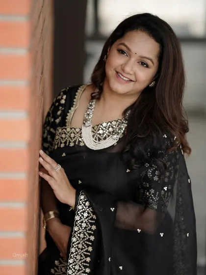 A client looking elegant in a black saree, paired with a stunning silver-based necklace.