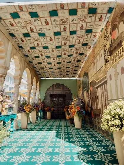 The entryway to the event, a long corridor with a printed ceiling and walls depicting scenes of Rajasthani life, immediately immersing guests in the theme.