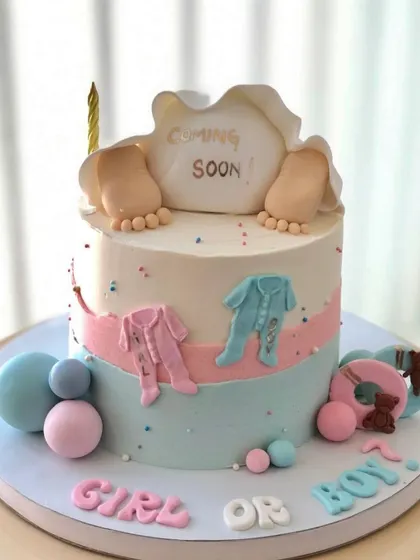 A cute "Girl or Boy" gender reveal cake, with tiny baby feet peeking out from under a blanket.