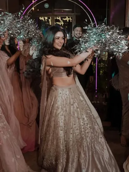 Crafting memories with beautiful entry concepts. Here, the bride makes her entrance with her bridesmaids, who are holding silver pom-poms to create a sparkling pathway.